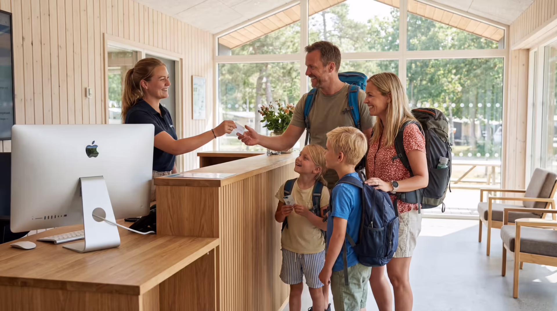 Familie checker ind i reception på campingplads med hjælp fra personale ved skranke